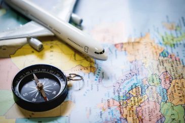 180 selective focus of miniature tourist on compass over map with plastic toy airplane,abstract background to travel concept.